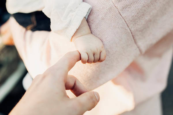 infant holding hands with parent